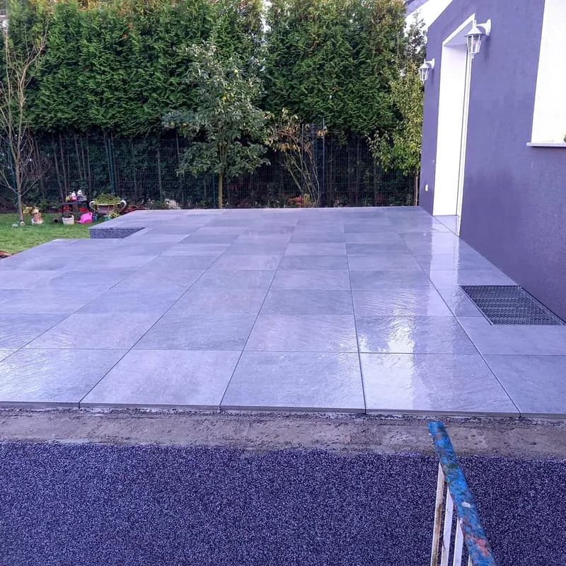 Großformatige Terrassenplatten vor der Hausfassade nach dem Regen