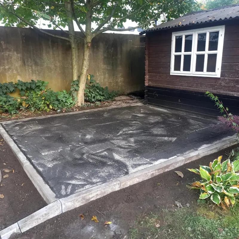 Befestigte Hoffläche vor einem Gartenhaus mit Baumbestand