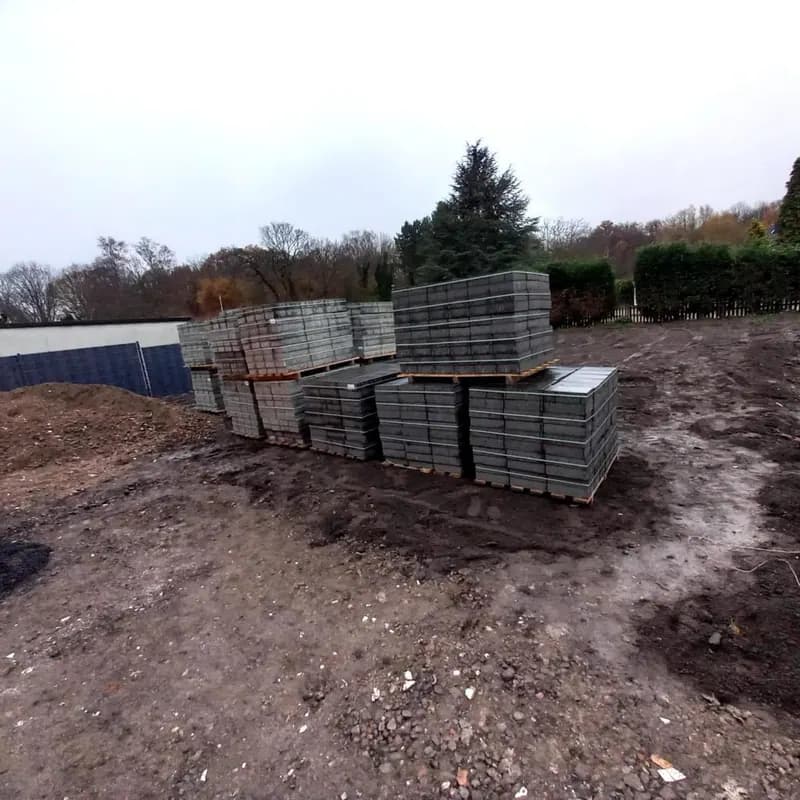 Paletten mit Pflastersteinen auf der vorbereiteten Baustelle