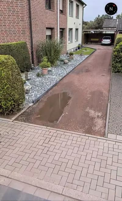 Gepflasterter Zugang neben einem Wohnhaus nach dem Regen