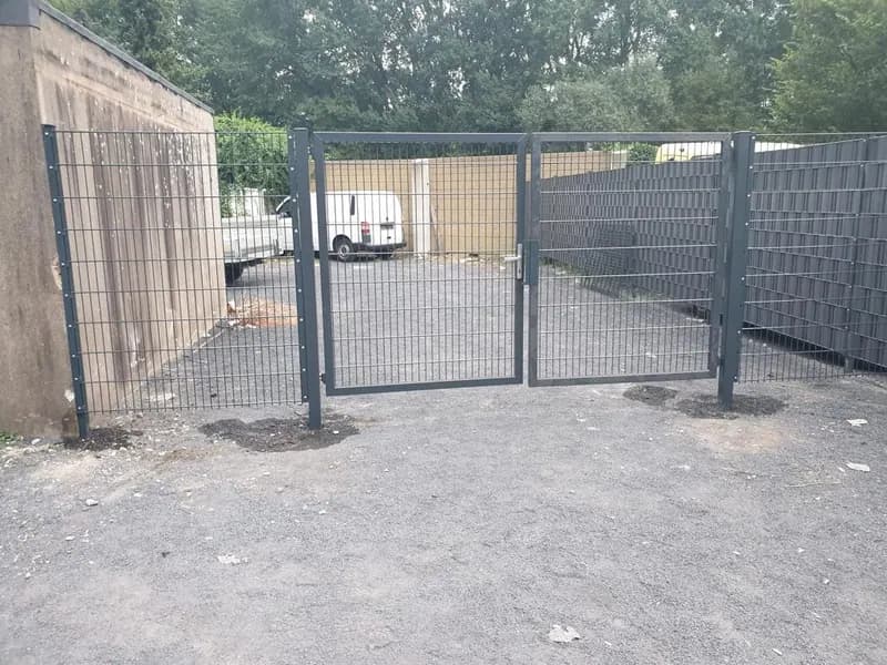 Doppelflügeltor mit Zaunanlage an einer befestigten Hoffläche