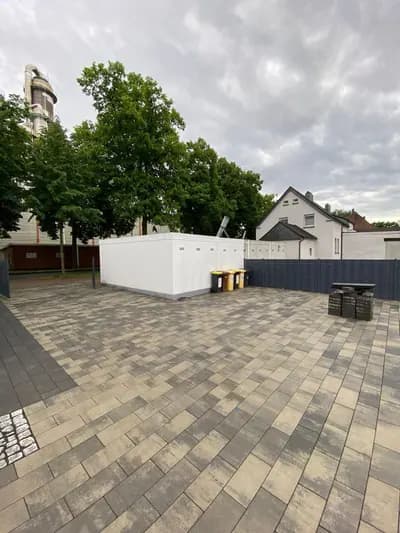 Großflächig gepflasterter Hof mit altem Baumbestand