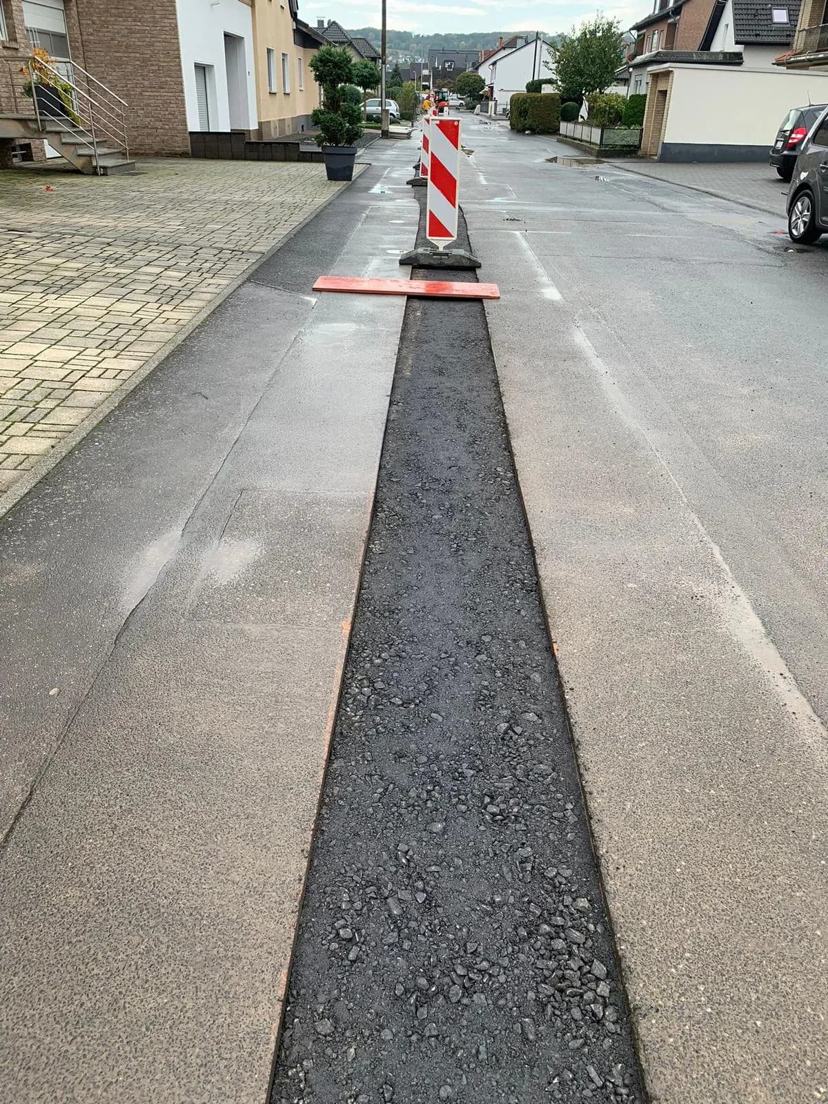 Wiederhergestellter Asphaltstreifen in der Fahrbahn mit Absperrbake