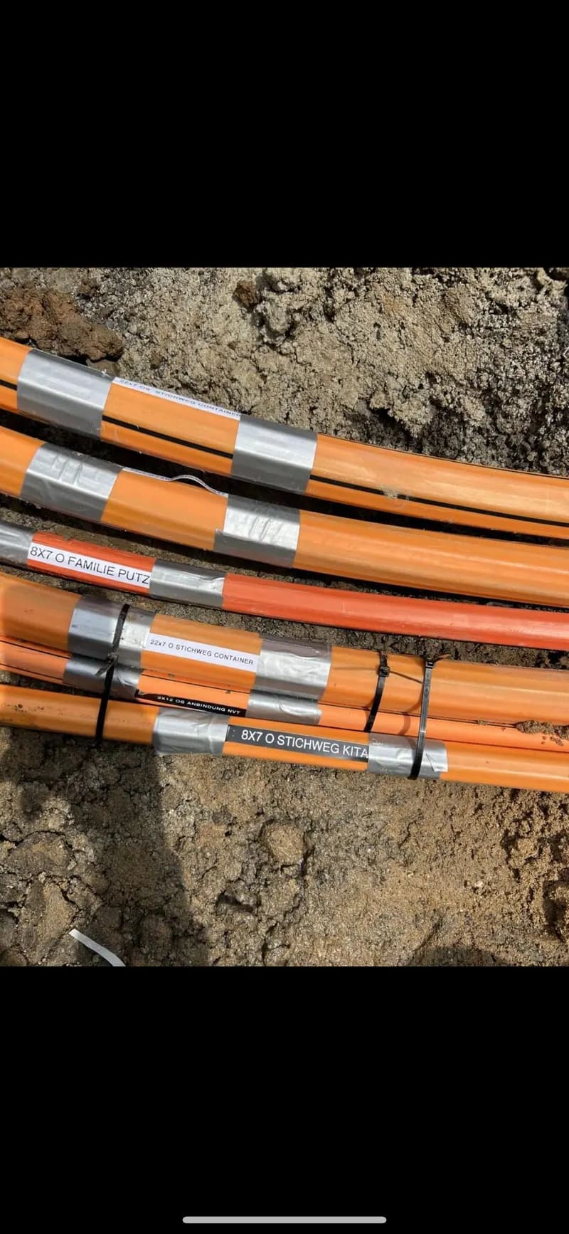 Mehrere orangefarbene Leerrohre nebeneinander im Kabelgraben