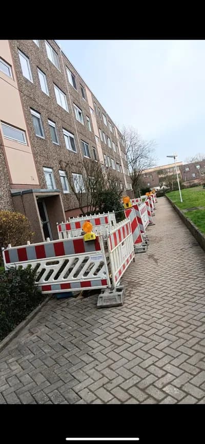Abgesperrte Gehwegbaustelle vor einem Mehrfamilienhaus