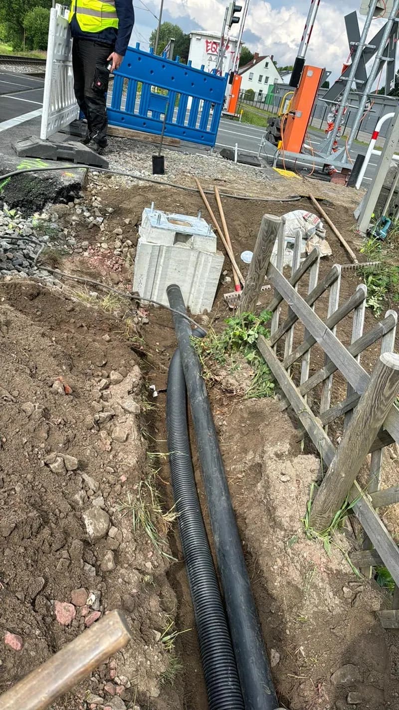 Verlegte Kabelschutzrohre im Graben neben der abgesperrten Gehwegbaustelle