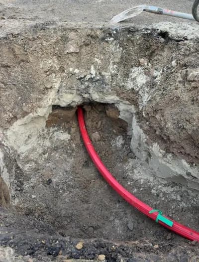 Rotes Kabelschutzrohr in der Fahrbahnaufgrabung