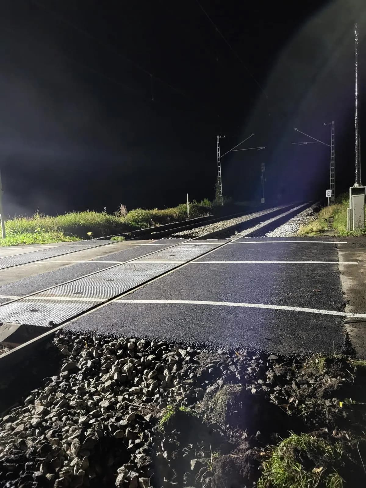 Fertiggestellter Bahnübergang mit neuer Asphaltdecke bei Nacht