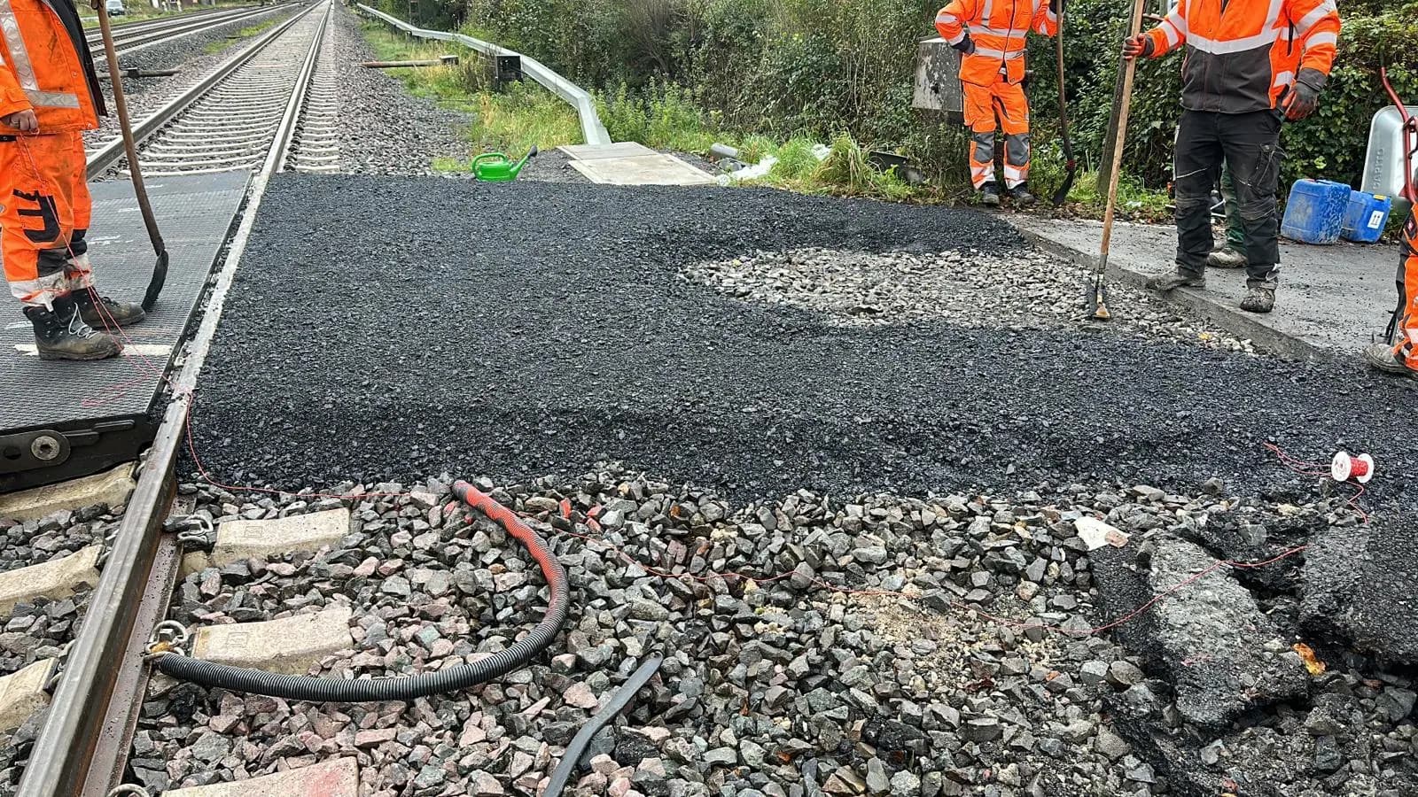 Asphalteinbau am Bahnübergang durch das RWB-Team in Warnkleidung