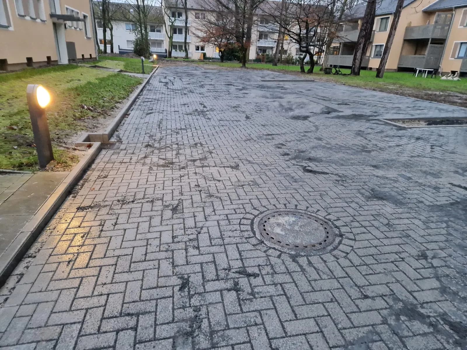 Gepflasterte Zufahrt mit eingebundener Schachtabdeckung in einer Wohnanlage