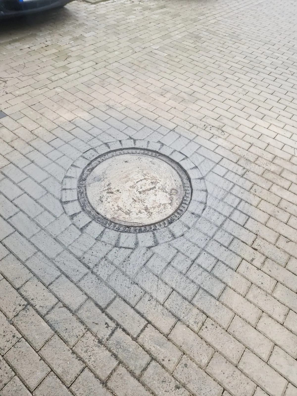 Nahaufnahme einer Schachtabdeckung, bündig in das Pflaster eingepasst