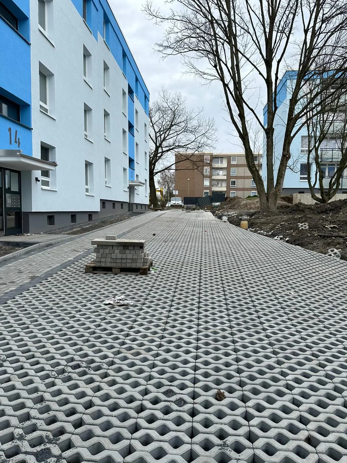Neu verlegtes Rasengitterpflaster vor einem Mehrfamilienhaus