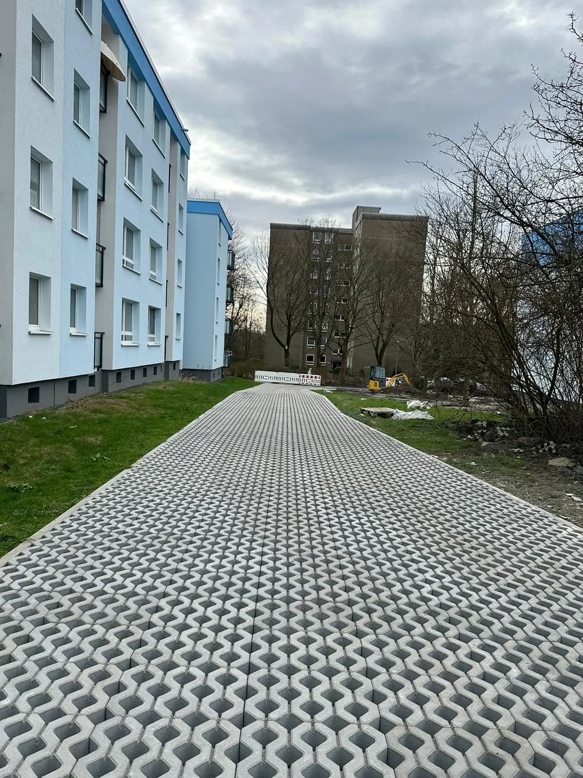Fertige Rasengitterfläche vor einem sanierten Mehrfamilienhaus