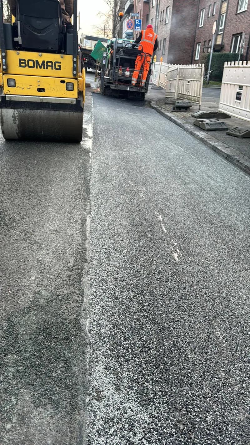 Walze verdichtet frisch eingebauten Asphalt in einer Wohnstraße