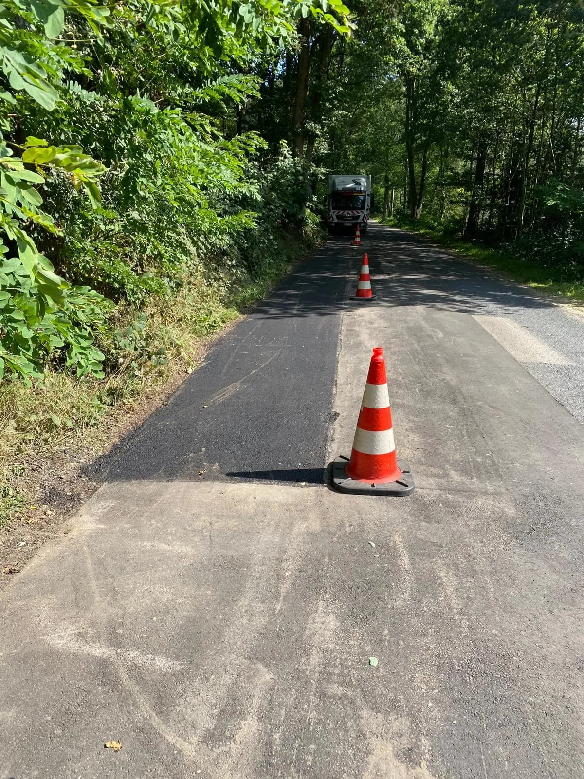 Frisch asphaltierter Fahrbahnabschnitt mit Leitkegel auf einer Landstraße