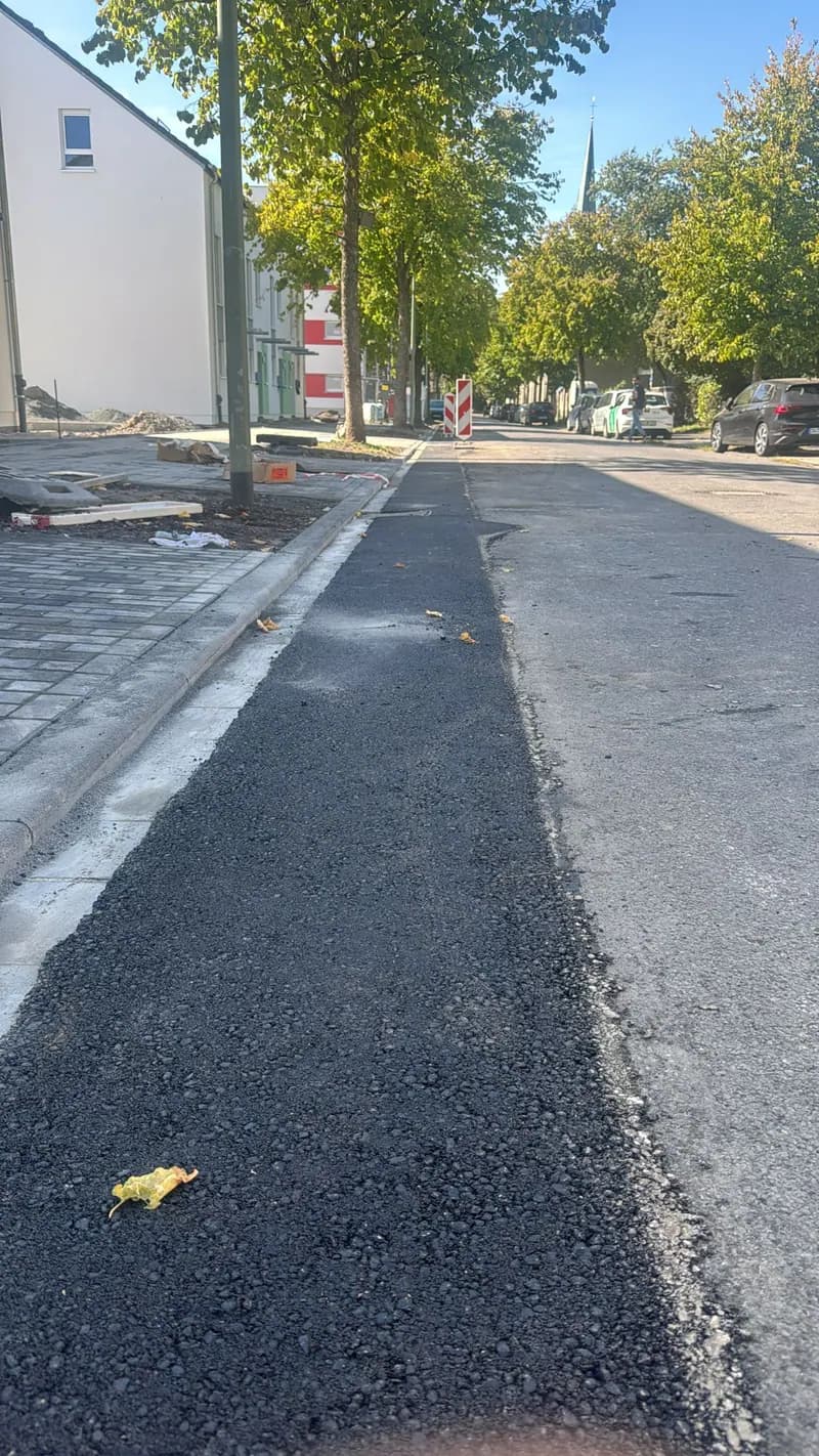 Neu asphaltierter Fahrbahnstreifen entlang einer Wohnstraße