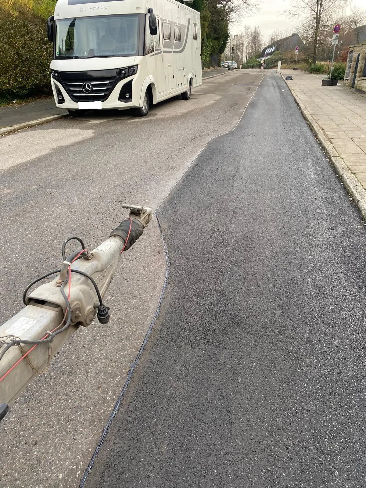 Asphaltarbeiten neben einem parkenden Wohnmobil in einer Anliegerstraße