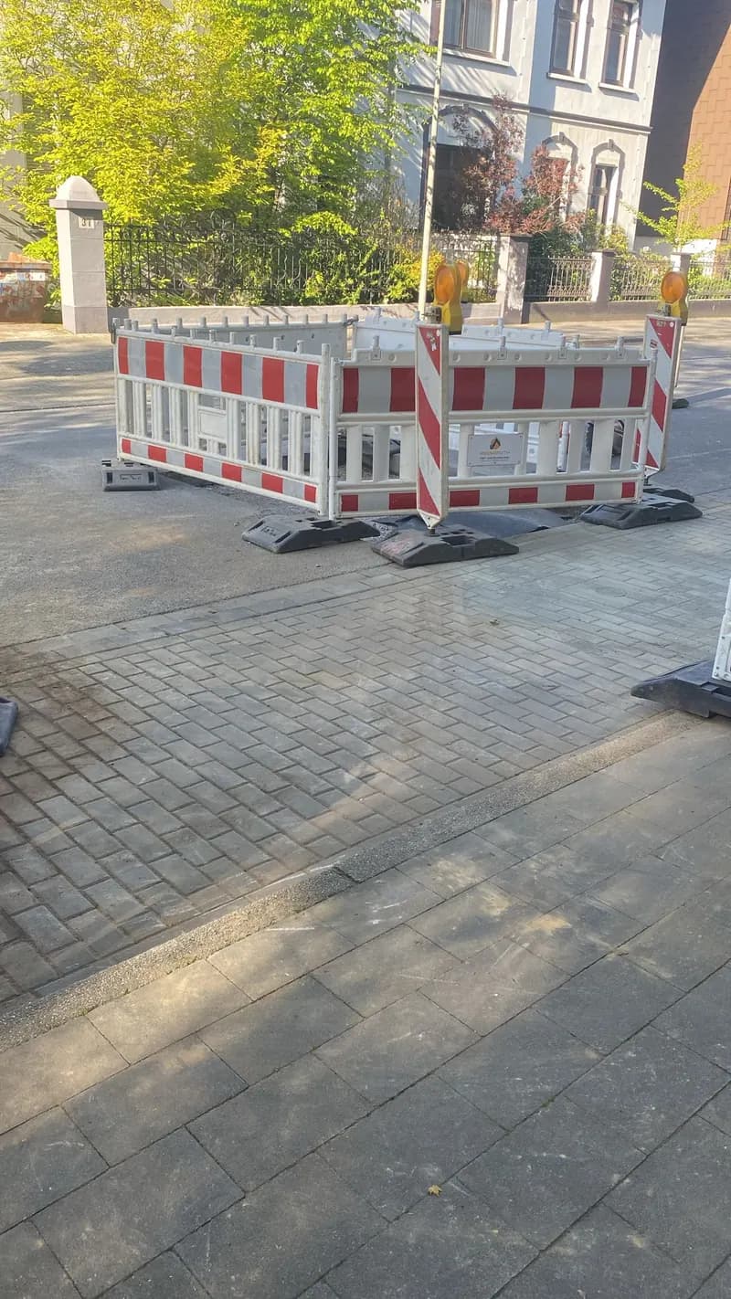 Absperrgitter auf gepflastertem Gehweg während der Bauarbeiten