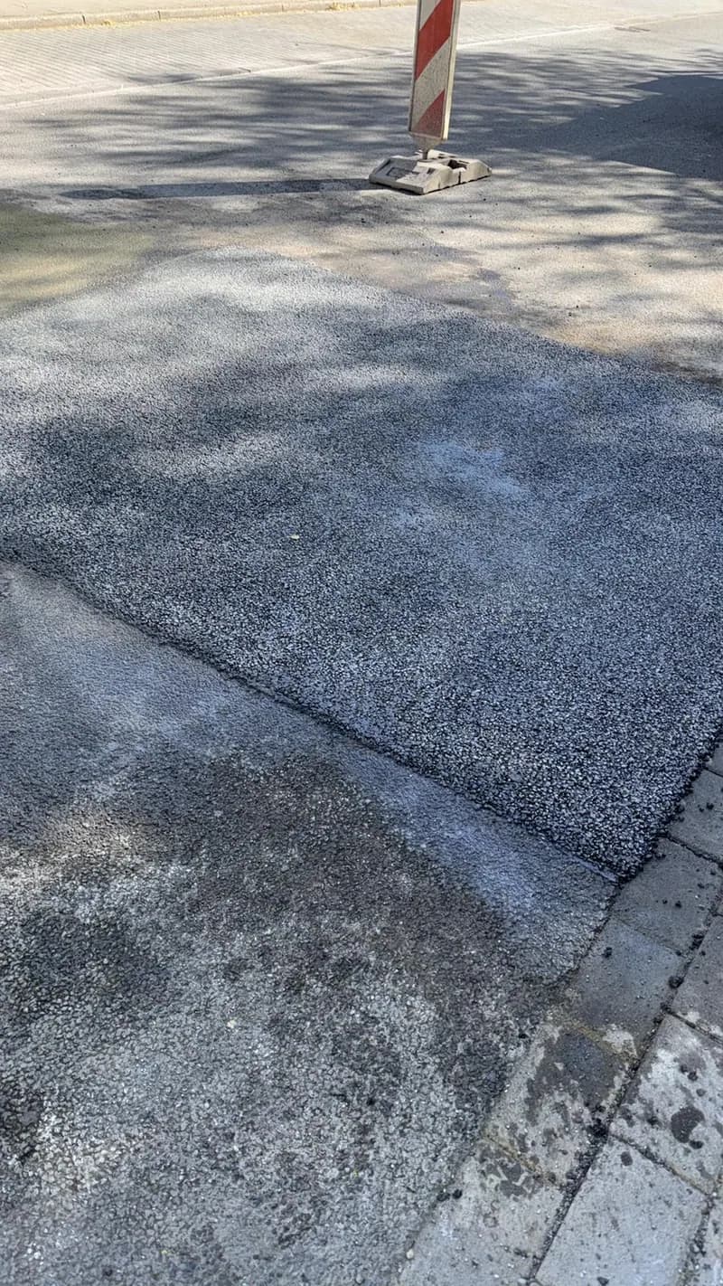 Verfüllte Aufgrabung im Gehweg mit Absperrbake