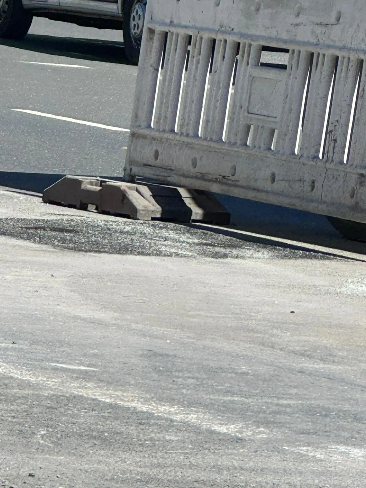 Absperrelement neben einer frisch verfüllten Aufgrabung am Fahrbahnrand