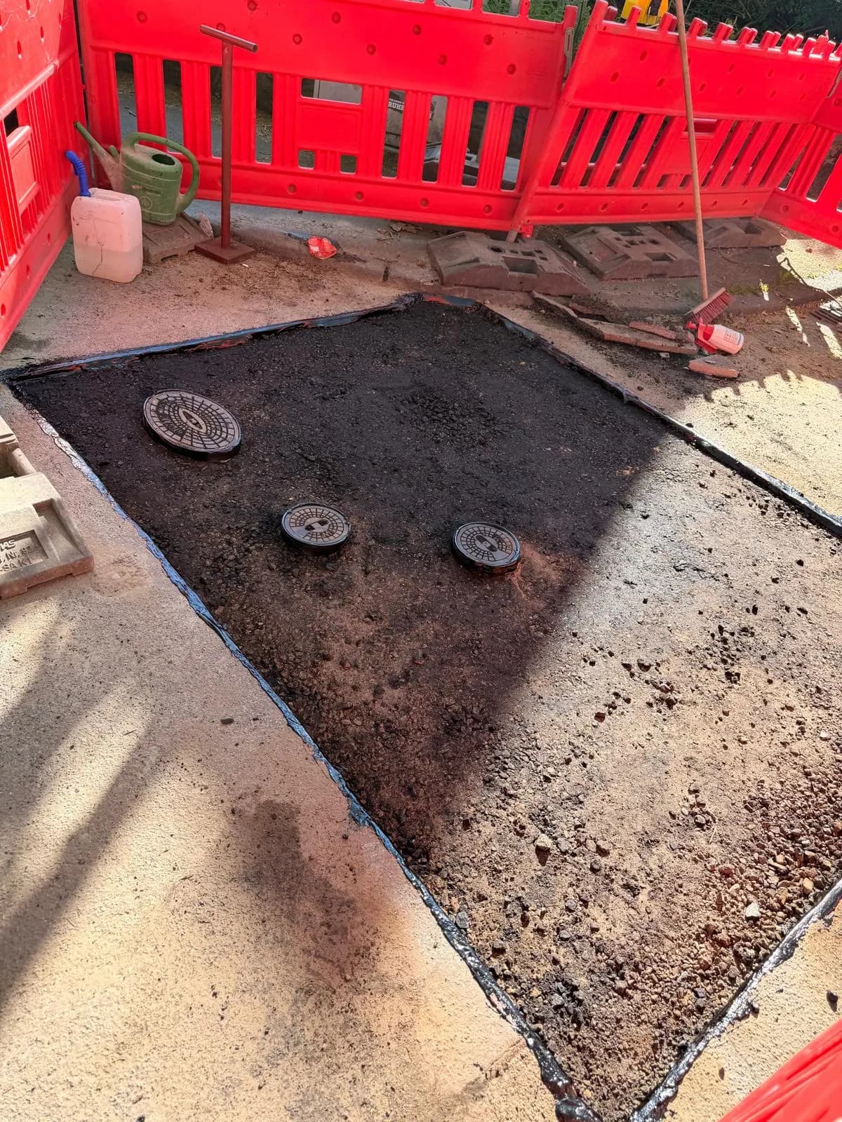 Aufgegrabener Bereich mit freigelegten Schachtabdeckungen hinter roter Absperrung