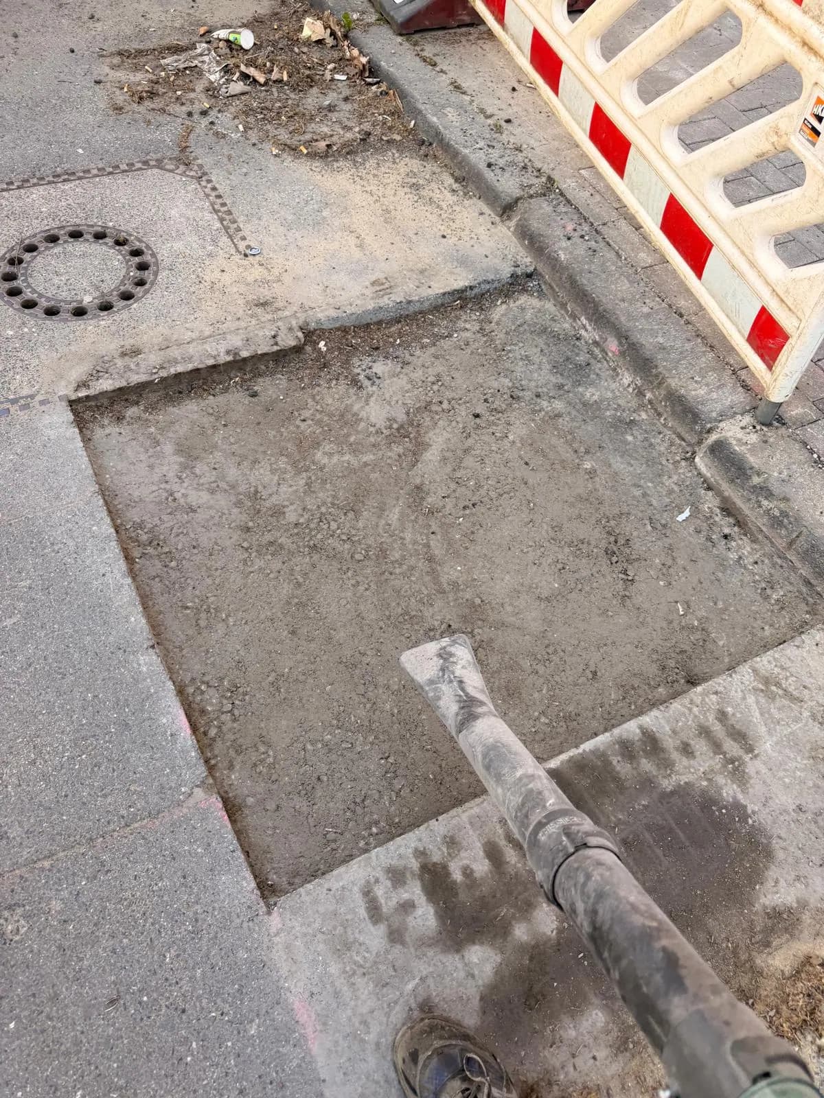 Freigelegte Schachtabdeckung im Gehweg während der Bauarbeiten