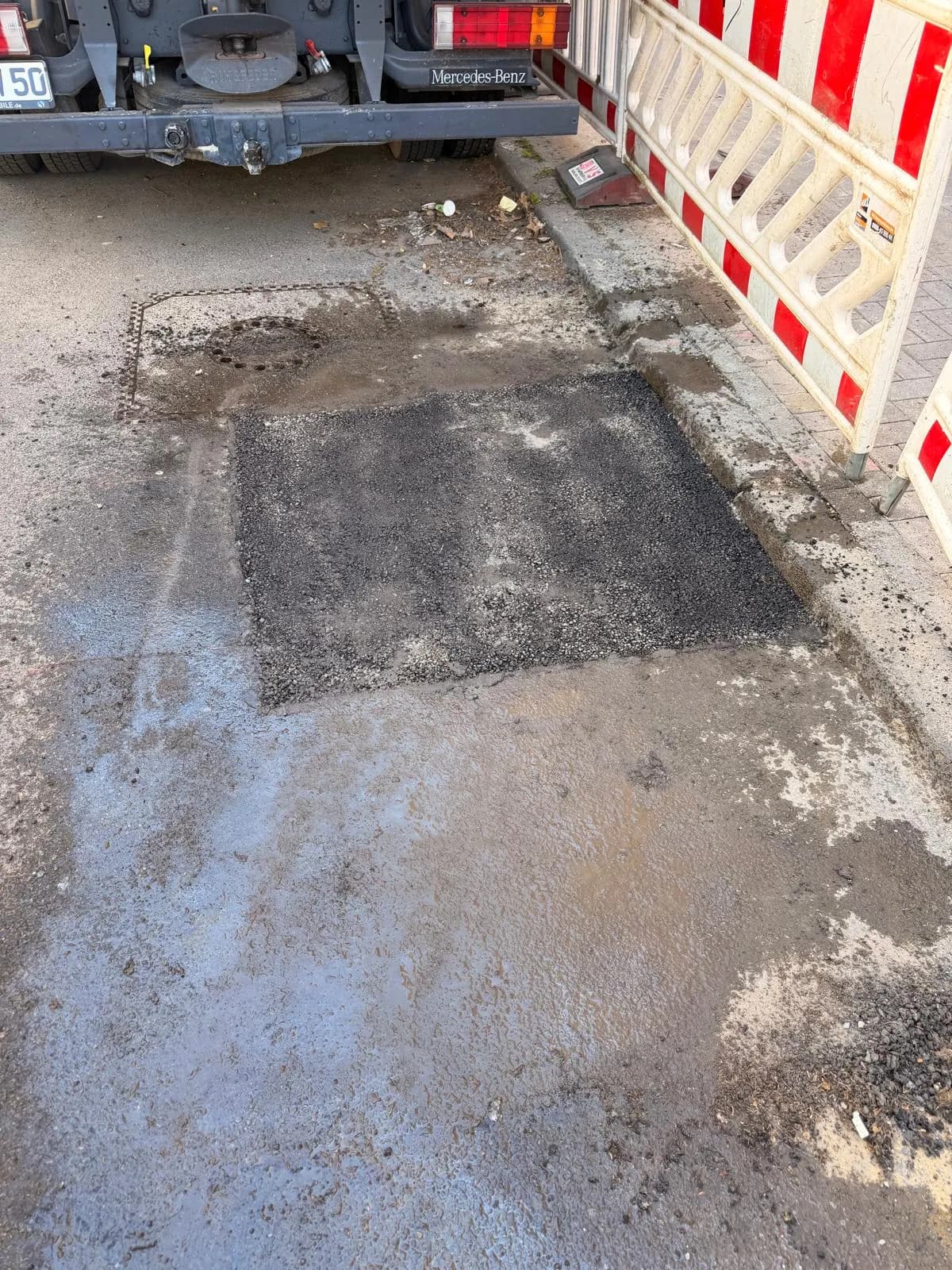Instandgesetzte Fahrbahnfläche neben einer Absperrbake