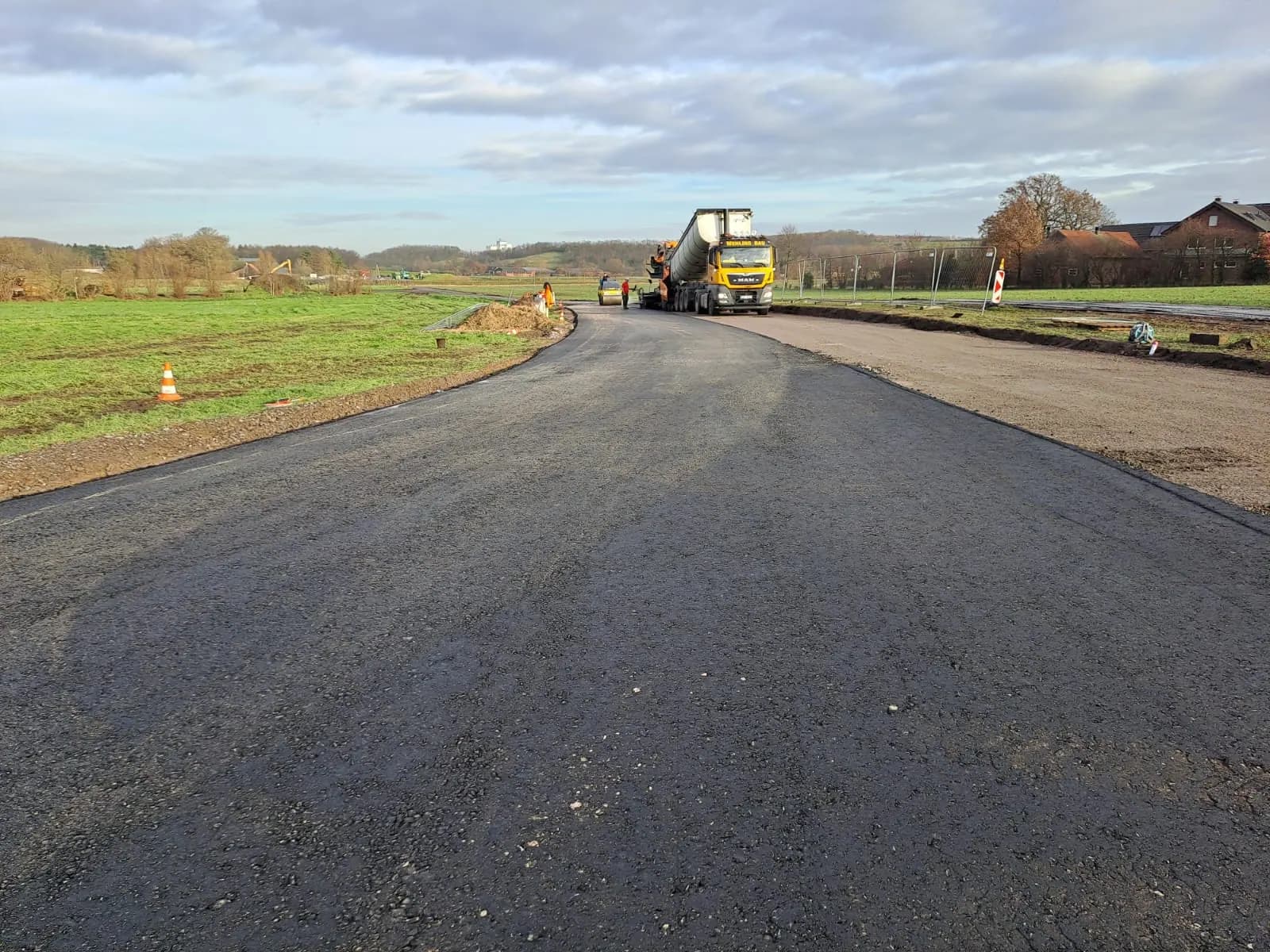 Fertiggestellter Wirtschaftsweg mit Walze am Horizont