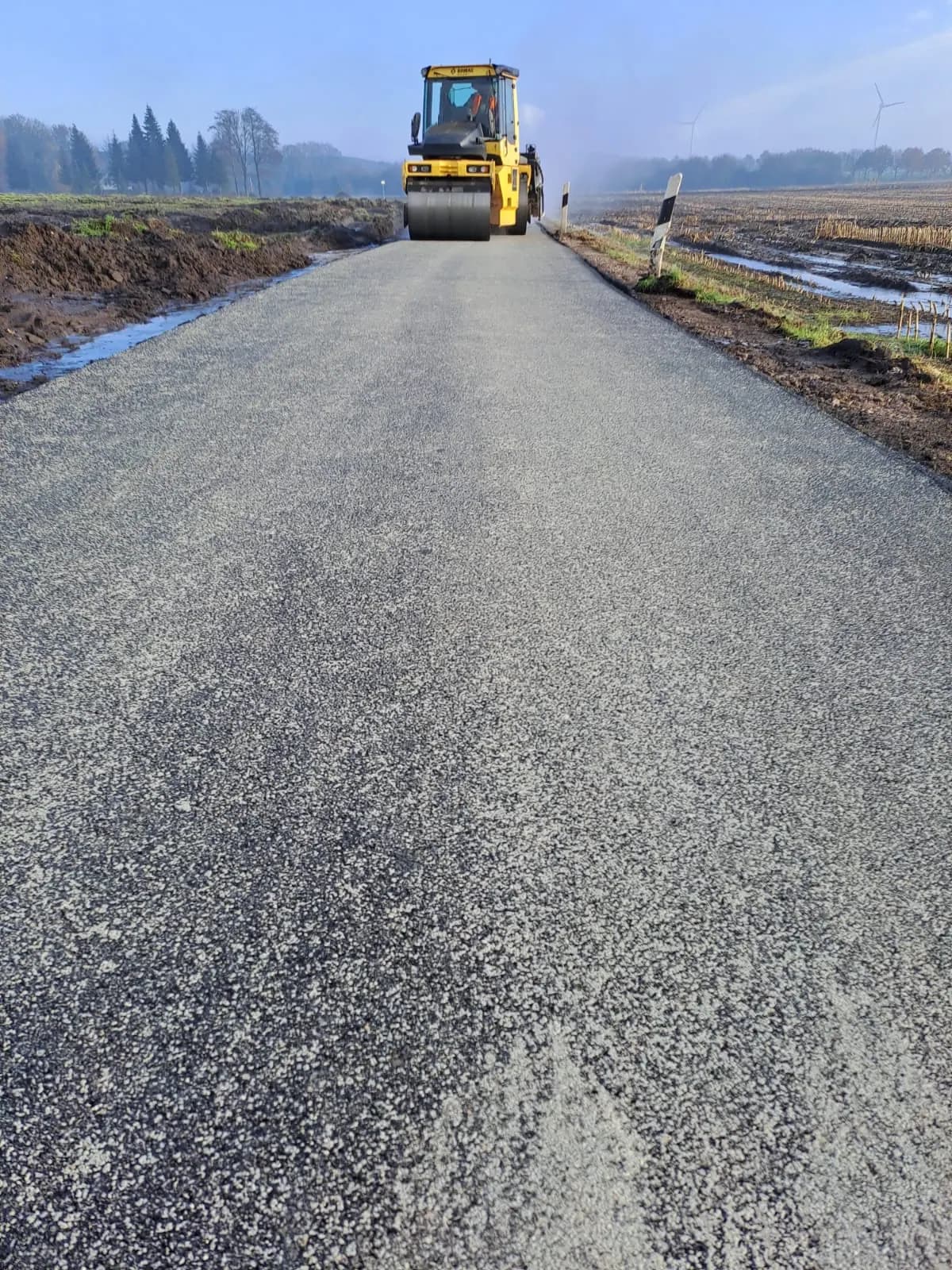 Walze auf dem frisch eingebauten Asphalt eines Feldwegs