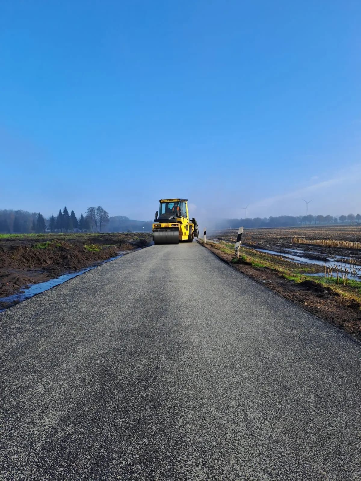 Walze verdichtet einen neuen Weg unter blauem Himmel