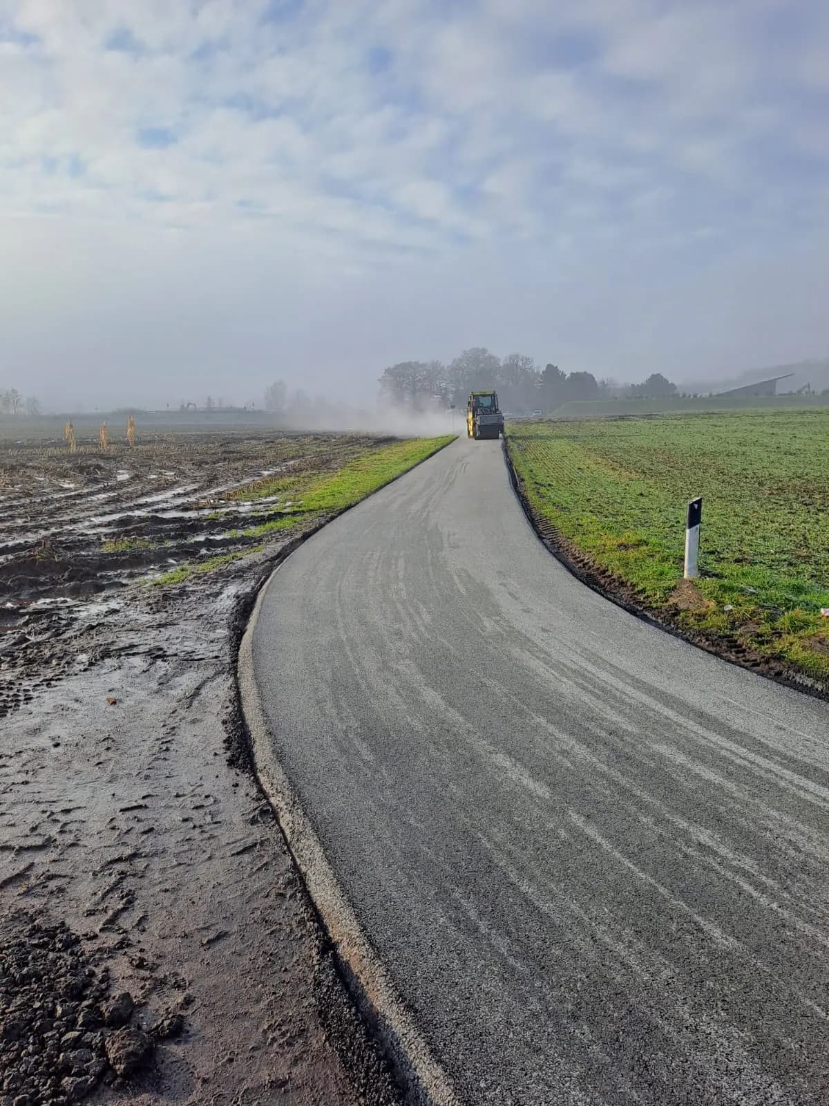 Fertiggestellter Wirtschaftsweg mit Walze am Horizont