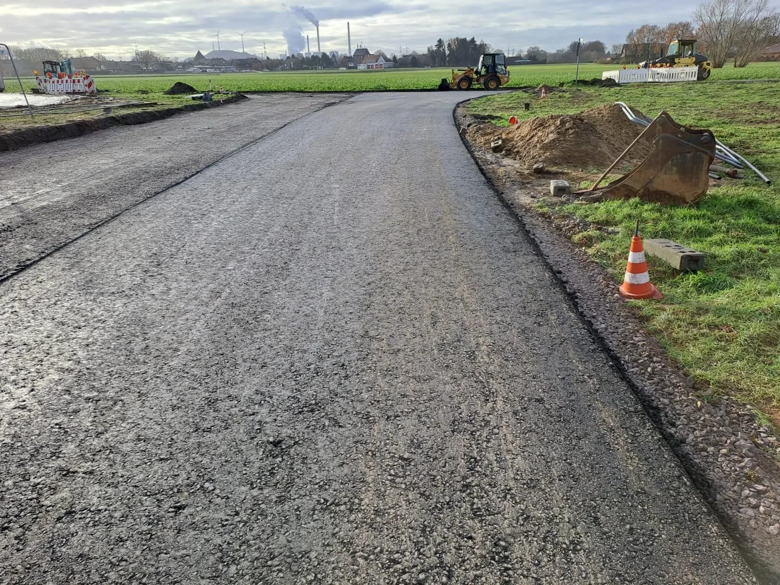 Neu gebaute Zufahrtsstraße mit Leitkegel und angrenzenden Erdmieten
