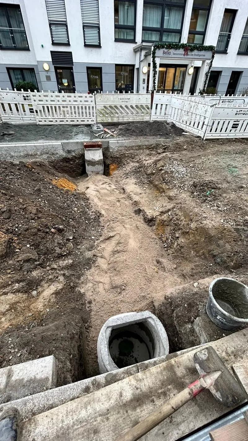 Schachtunterteil und Rohre im Graben vor einem Neubau