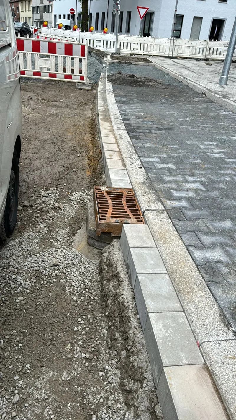 Neu gesetzte Bordsteinkante mit Straßeneinlauf an einer Baustelle