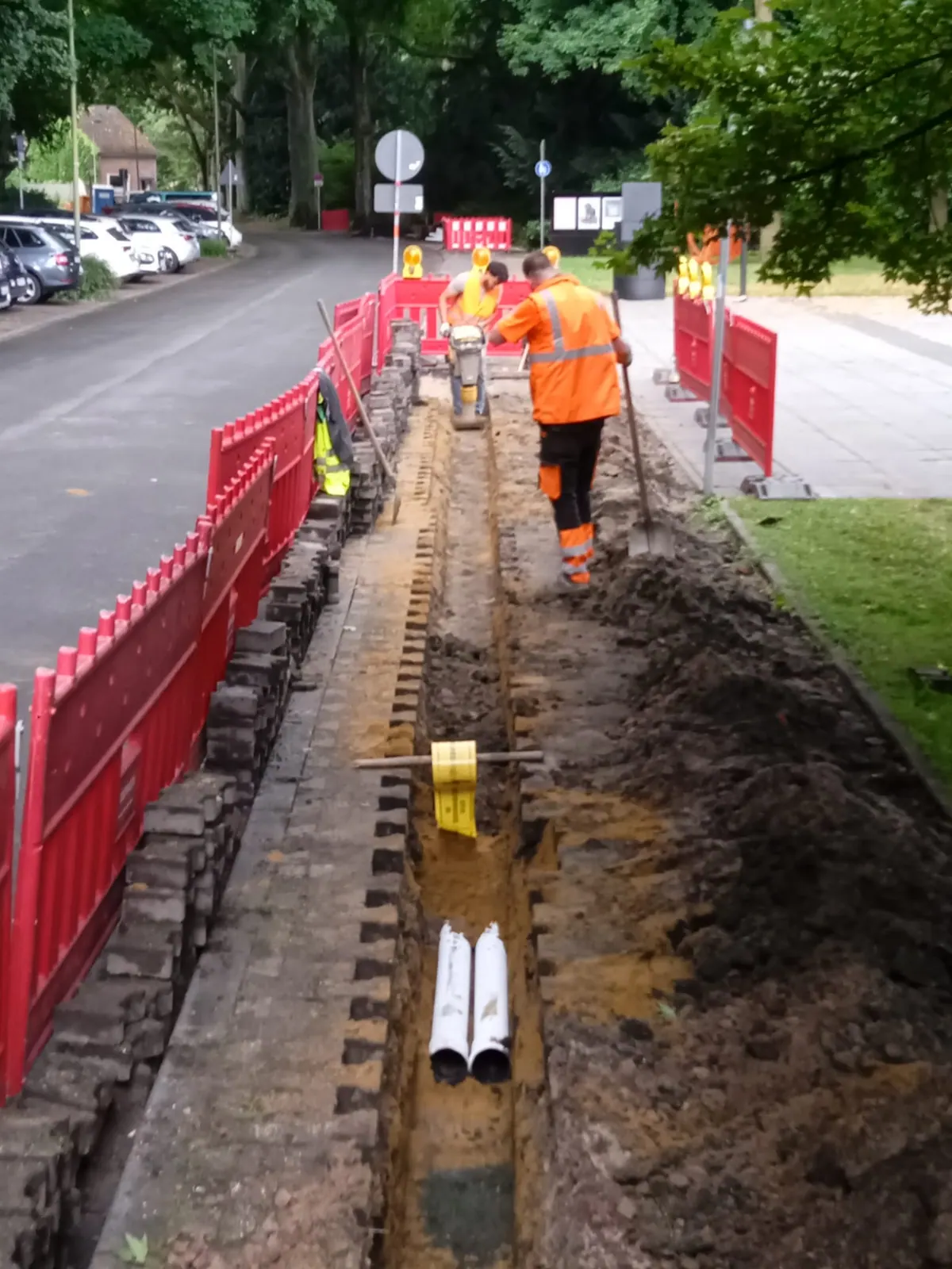 Team in Warnkleidung arbeitet an einem gesicherten Leitungsgraben