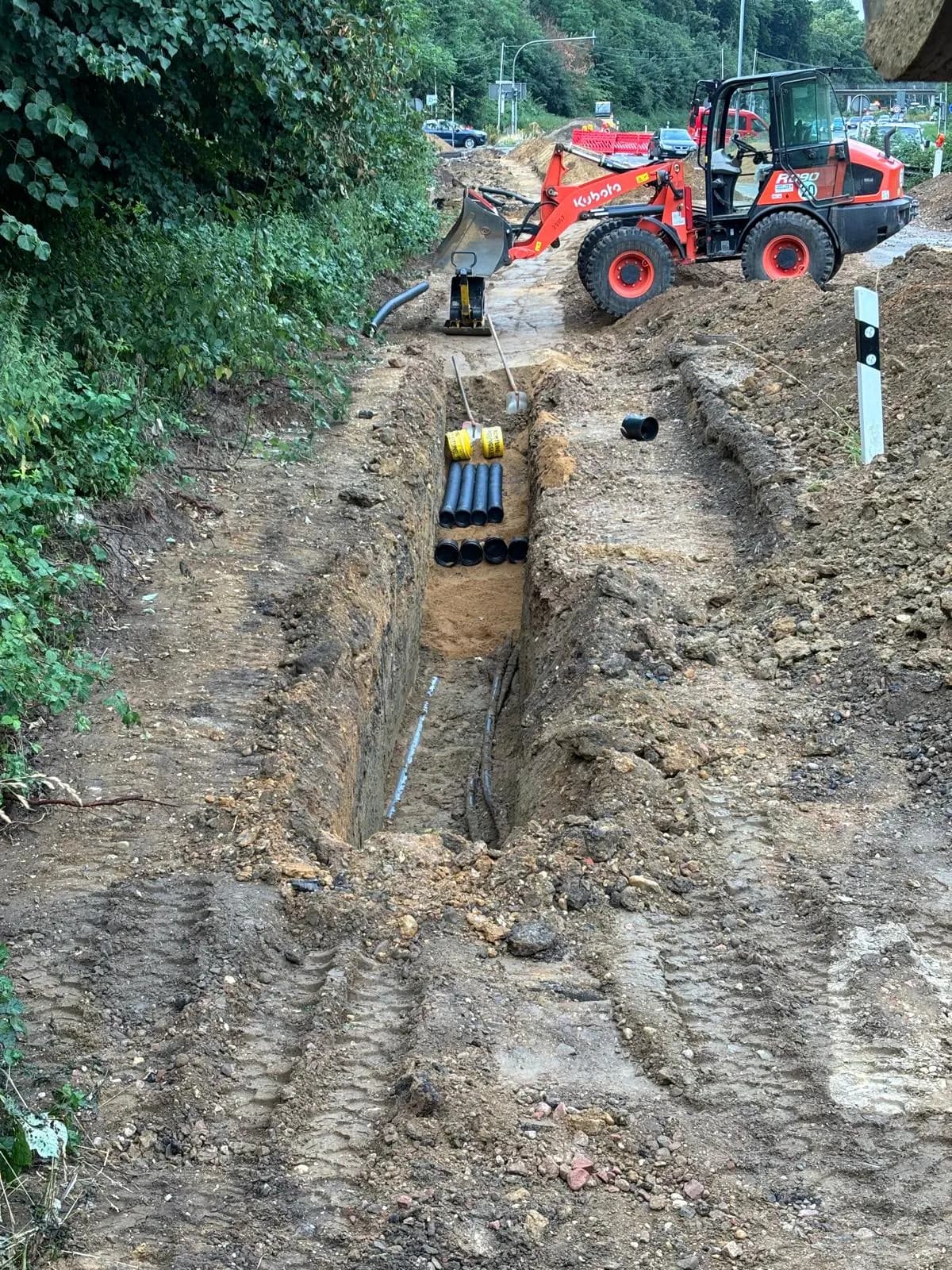 Radlader an einer Grabenbaustelle mit verlegten Rohren