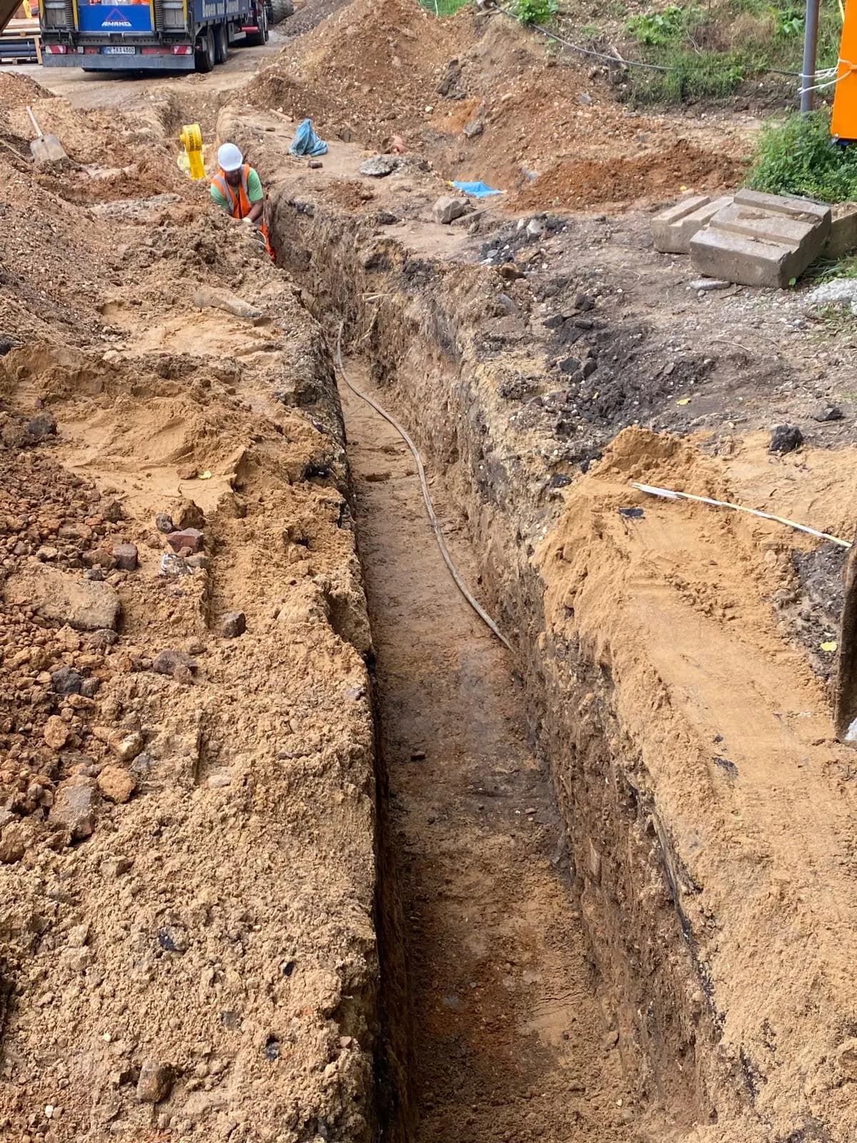 Schmaler Leitungsgraben durch sandigen Boden auf einer Großbaustelle