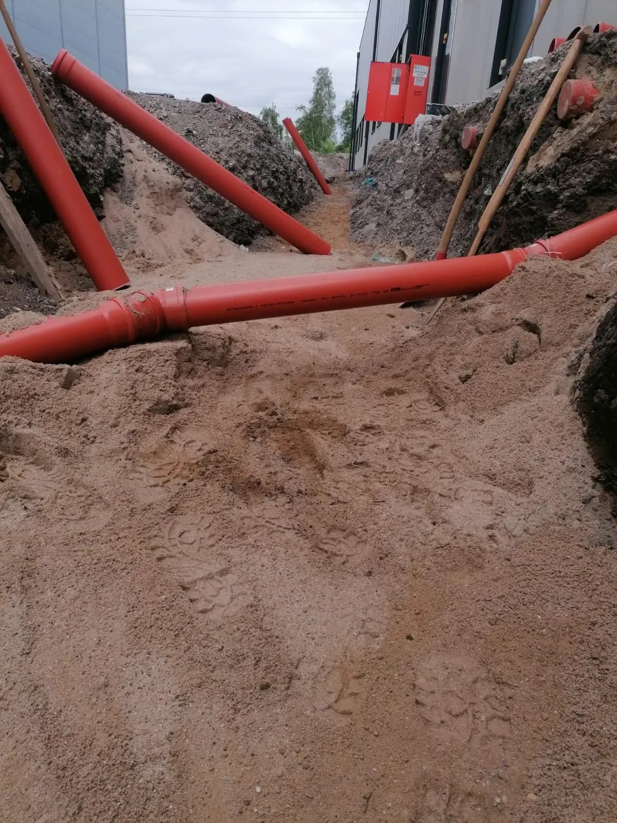 Mehrere KG-Rohrstränge kreuzen sich in der Baugrube