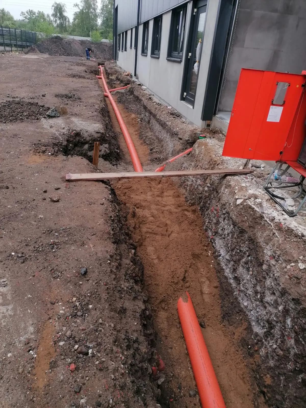 Rohrleitung im Graben entlang einer Gewerbehalle